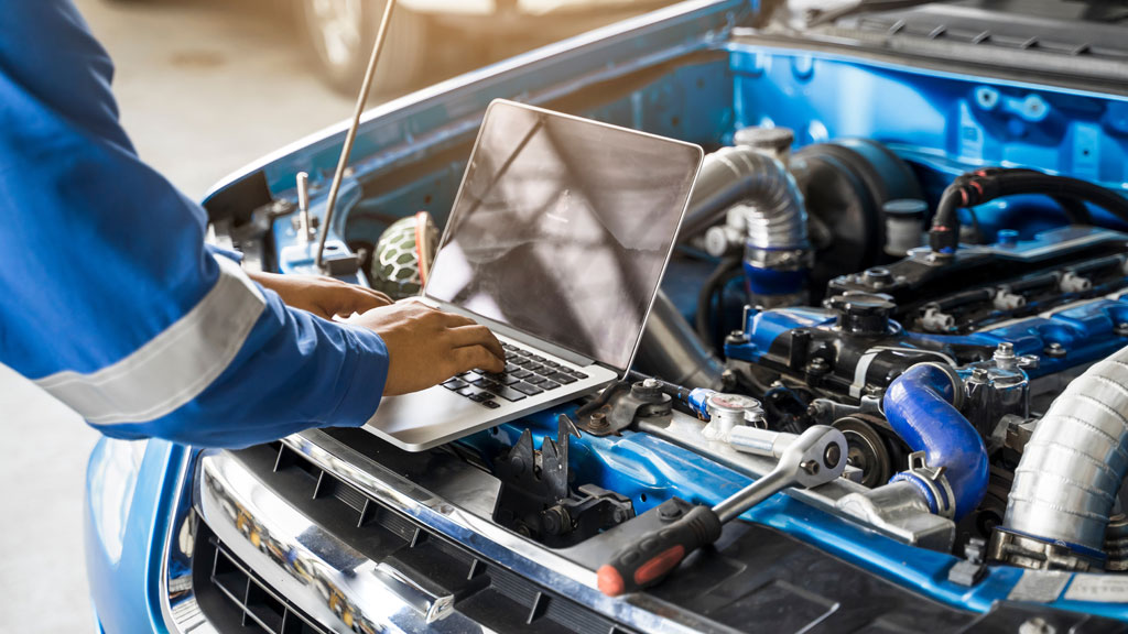 Compartiment moteur diesel examiné avec tablette de diagnostic dans un environnement d'atelier mécanique