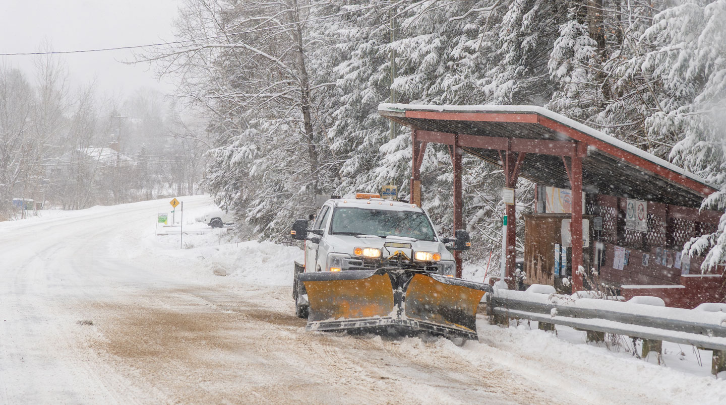Fourgonnette professionnelle de service de toiture avec échelle et équipement, stationnée devant une résidence canadienne en hiver, prête pour intervention d'urgence